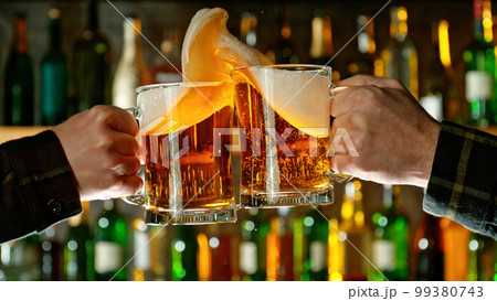 Close-up view of a two glasses of beer in hands. 99380743