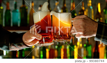 Close-up view of a two glasses of beer in hands. 99380744