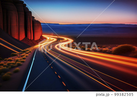 Highway between towering steep mountains and a wide plain with glowing light trails from cars at night, made with generative AI Highway between towering steep mountains and a wide plain with glowing light trails from cars at night, made with generative AI 99382505