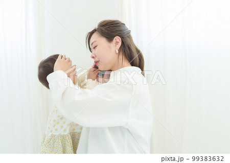 赤ちゃんの熱を測りながら病院に電話する母親 99383632