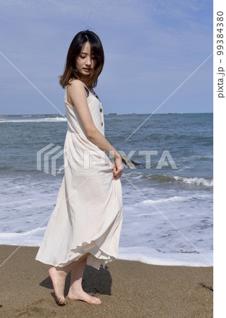 君ヶ浜の海岸でポーズをとる白いワンピース姿の若い女性 君ヶ浜の海岸でポーズをとる白いワンピース姿の若い女性 99384380