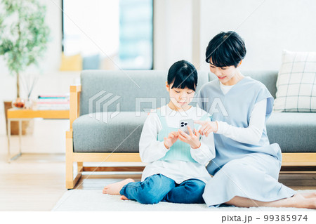 リビングでスマートフォンを操作する親子（母子） 99385974