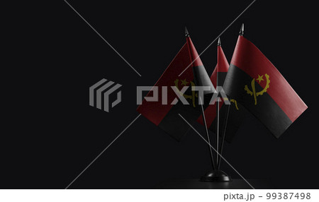 Small national flags of the Angola on a black background 99387498