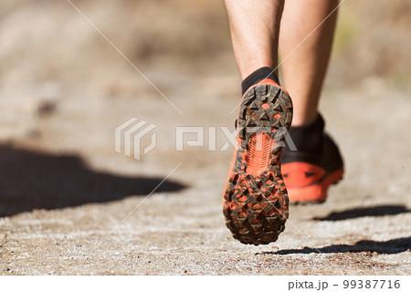 Trail running athlete exercising for fitness and health outdoors on mountain pathway, closeup of running shoes in action Trail running athlete exercising for fitness and health outdoors on mountain pathway, closeup of running shoes in action 99387716