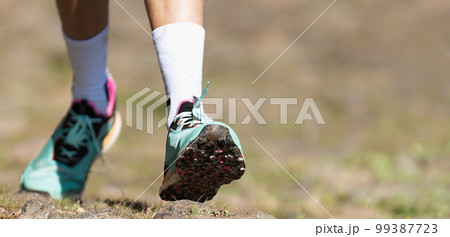 Trail running athlete exercising for fitness and health outdoors on mountain pathway, closeup of running shoes in action 99387723