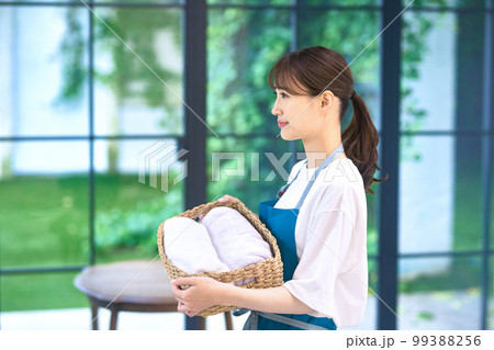 洗濯物を運ぶエプロン姿の主婦 99388256