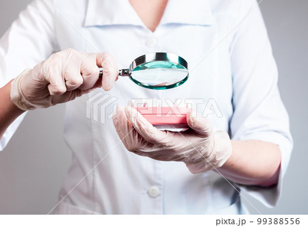 Dentist with magnifying glass over jaw model with teeth. Dental checkup conducting. Decay, gum diseases prevention and detection. Health care, stomatology concept 99388556