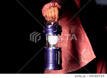 Girl hand holding glowing vintage lantern closeup. Lightning way in dark Girl hand holding glowing vintage lantern closeup. Lightning way in dark 99388584