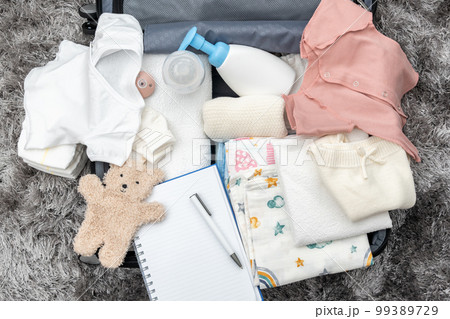Open bag for maternity hospital on the floor. Suitcase with baby clothes prepared for newborn birth. Concept of getting ready for the maternity hospital 99389729