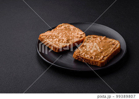Nutritious sandwich consisting of bread and peanut butter on a black ceramic plate Nutritious sandwich consisting of bread and peanut butter on a black ceramic plate 99389807