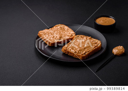 Nutritious sandwich consisting of bread and peanut butter on a black ceramic plate Nutritious sandwich consisting of bread and peanut butter on a black ceramic plate 99389814