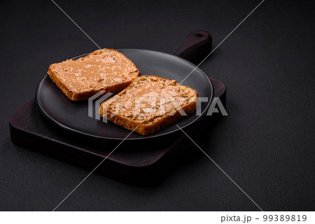 Nutritious sandwich consisting of bread and peanut butter on a black ceramic plate Nutritious sandwich consisting of bread and peanut butter on a black ceramic plate 99389819