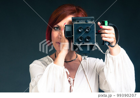 beautiful red-haired woman with a vintage photo camera  99390207