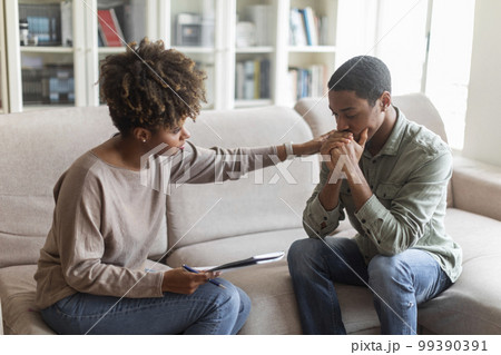 Young african woman psychologist consoling upset man 99390391