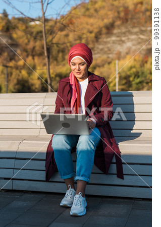 Female muslim arabian student in hijab holding laptop outdoors - freelancer, blogger and diversity concept Female muslim arabian student in hijab holding laptop outdoors - freelancer, blogger and diversity concept 99391138