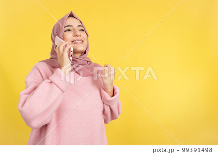 Happy muslim woman celebrating while talking to the mobile Happy muslim woman celebrating while talking to the mobile 99391498
