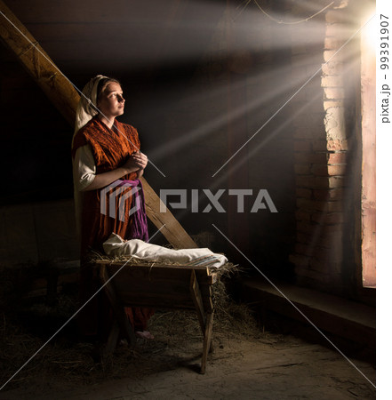 Mary sits in the stable near the manger with the baby 99391907