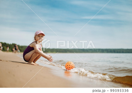 cute little girl playing with rubber ball in sea 99393336