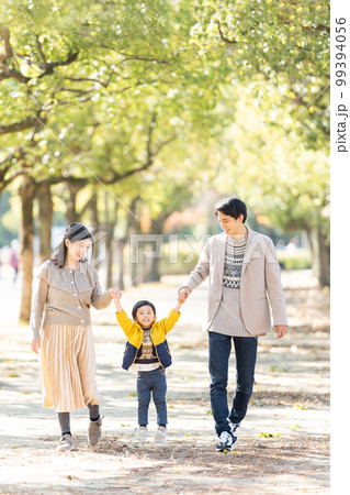 並木道を手をつないで歩く家族 99394056