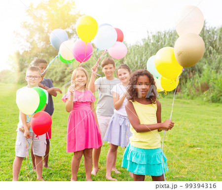 Children with balloons on field 99394316