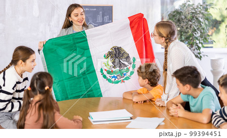 Teacher showing Mexico flag to group of schoolchildren Teacher showing Mexico flag to group of schoolchildren 99394451