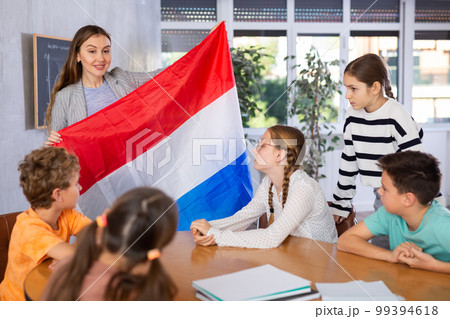 Teacher showing Holland flag to group of schoolchildren Teacher showing Holland flag to group of schoolchildren 99394618