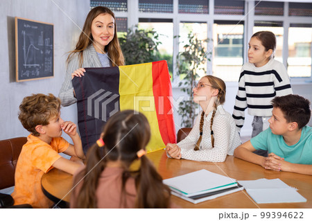 Teacher showing Belgium flag to group of schoolchildren Teacher showing Belgium flag to group of schoolchildren 99394622