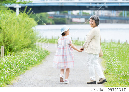 手をつないで歩く女の子とお婆ちゃん 99395317