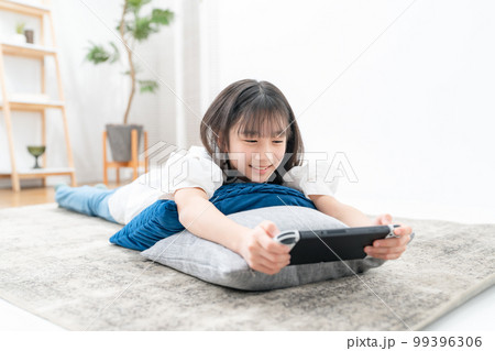 寝転んでゲームをする女の子 99396306