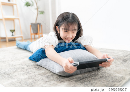 寝転んでゲームをする女の子 99396307
