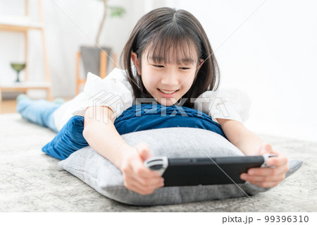 寝転んでゲームをする女の子 99396310