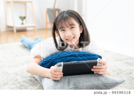 寝転んでゲームをする女の子 99396318