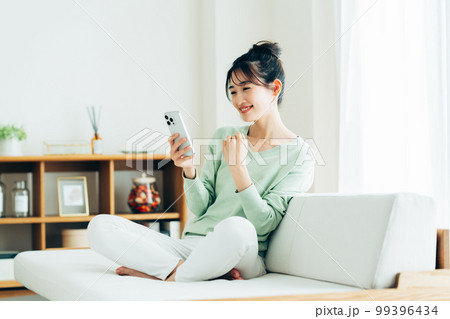 リビングでスマホを見る若い女性 リビングでスマホを見る若い女性 99396434