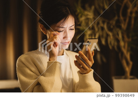 夜にスマホを見る女性 99398649