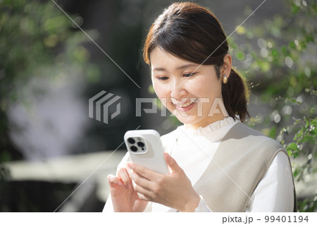 屋外でスマホを見てタップする女性 99401194