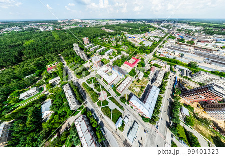 Aerial city view with crossroads and roads, houses, buildings, parks and parking lots. Sunny summer panoramic image 99401323