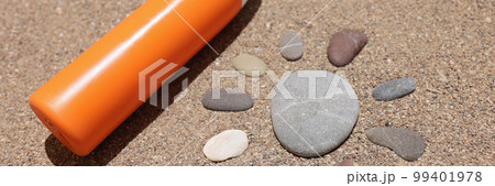 Sun made of stones on sea sand orange liquid bottle of cream or lotion Sun made of stones on sea sand orange liquid bottle of cream or lotion 99401978