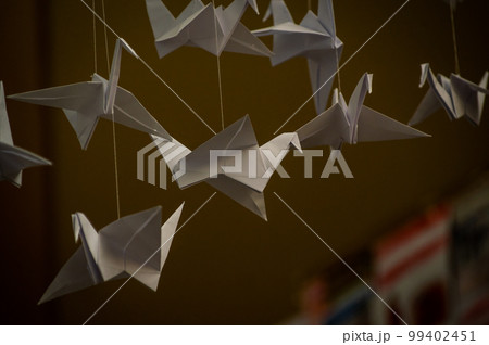 Japanese folded Origami cranes hanging on with strings. Hundreds handmade paper birds isolated with copy space. 1000 thousand crane sculpture topic. Symbol of peace, faith, health, wishes, hope 99402451