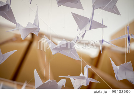 Japanese folded Origami cranes hanging on with strings. Hundreds handmade paper birds isolated with copy space. 1000 thousand crane sculpture topic. Symbol of peace, faith, health, wishes, hope Japanese folded Origami cranes hanging on with strings. Hundreds handmade paper birds isolated with copy space. 1000 thousand crane sculpture topic. Symbol of peace, faith, health, wishes, hope 99402600