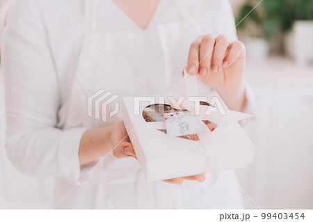 Girl in a white uniform holding chocolate-covered strawberries in a gift box Girl in a white uniform holding chocolate-covered strawberries in a gift box 99403454