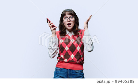 Surprised young female looking at smartphone on white background 99405288