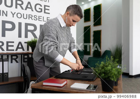 mature woman with a short haircut in the office working with documents 99406988