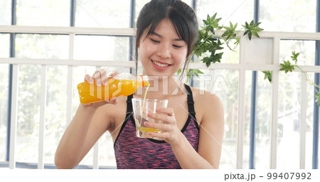 Women hands holding cold orange juice fresh fruit cool drinking. Asian women smile laugh look at camera health care home fitness lifestyle. Beautiful female pouring orange juice from cocktail bottle 99407992