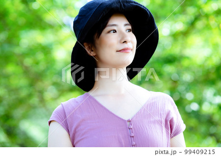 新緑の公園でリフレッシュする帽子をかぶったワンピースの女性 新緑の公園でリフレッシュする帽子をかぶったワンピースの女性 99409215