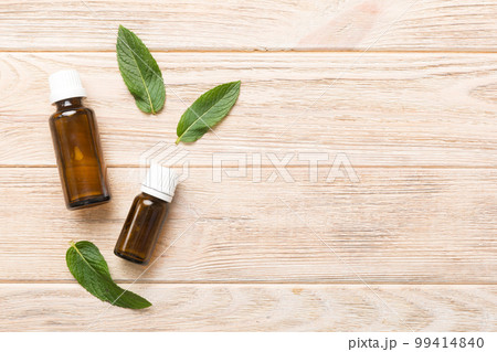 Natural Mint Essential Oil in a Glass Bottle. organic cosmetics with herbal extracts of mint on colored background 99414840