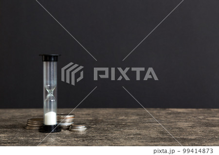 Deadline and time is money concept with hourglass and US coins currency. sand clock time for saving concept Deadline and time is money concept with hourglass and US coins currency. sand clock time for saving concept 99414873