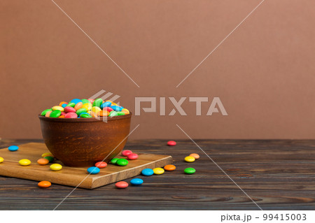 Multicolored candies in a bowl on a colored background. birthday and holiday concept. Top view with copy space 99415003