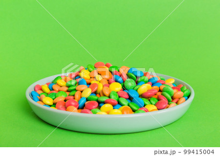 Multicolored candies in a bowl on a colored background. birthday and holiday concept. Top view with copy space 99415004