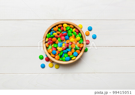 Multicolored candies in a bowl on a colored background. birthday and holiday concept. Top view with copy space 99415051