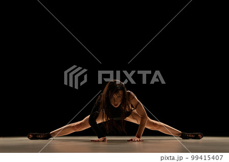 On twine. Deep look. Young woman in bodysuit and heels dancing, performing over black background. Concept of contemporary dance style, art On twine. Deep look. Young woman in bodysuit and heels dancing, performing over black background. Concept of contemporary dance style, art 99415407